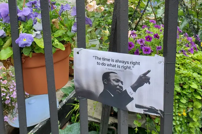 Flowers and an inspirational quote from Martin Luther King, Jr. adorn a wrought iron fence in Brooklyn.